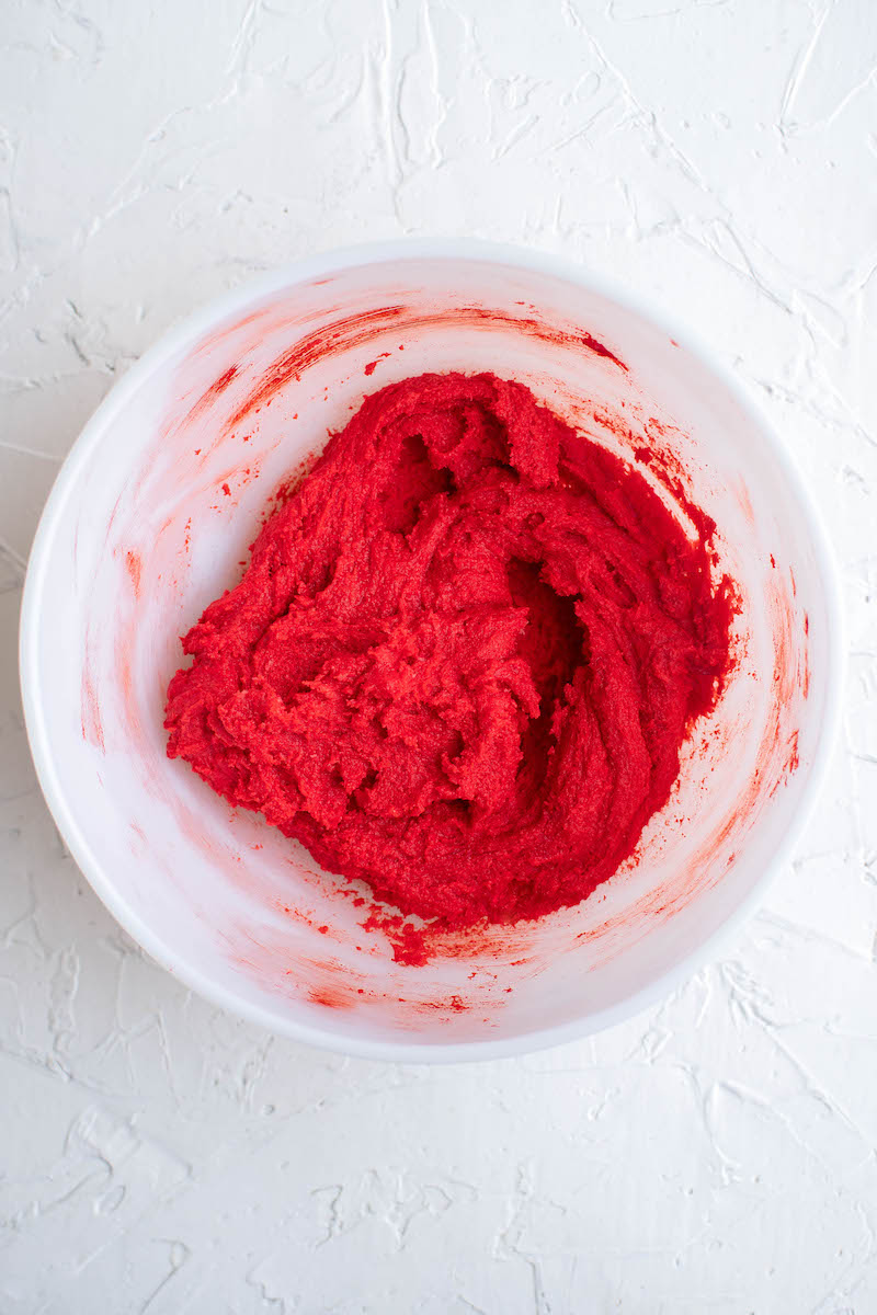 Bright red cookie dough in a bowl.