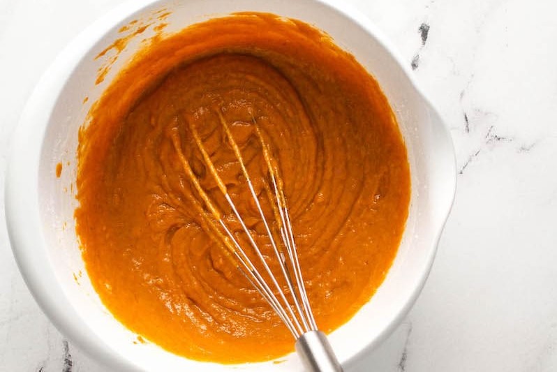 Pumpkin bread batter in a mixing bowl with a whisk