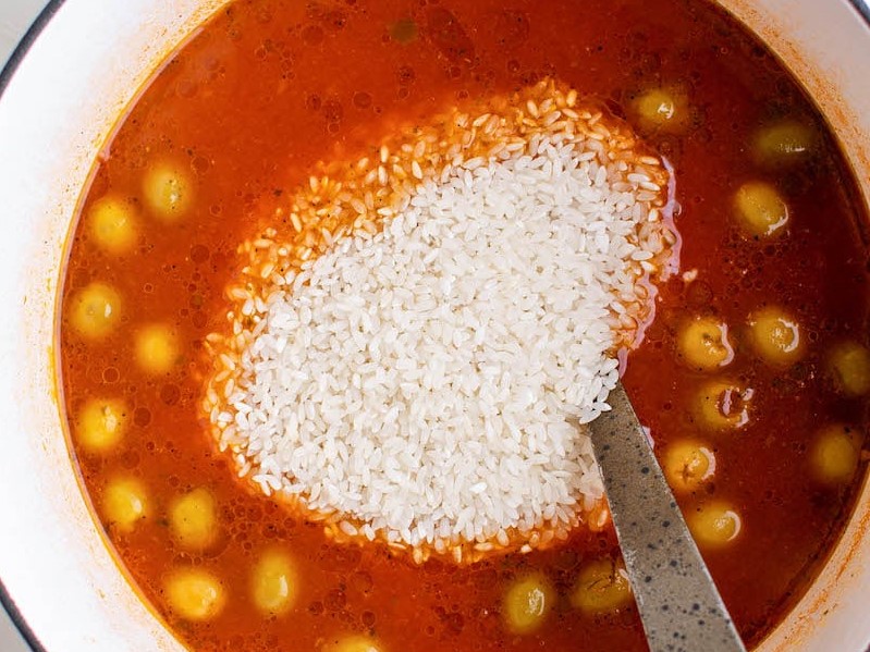 Rice added to tomato mixture for Arroz Con Gandules in a stock pot