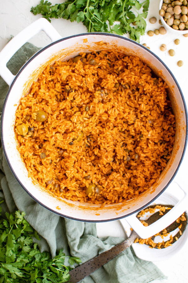Freshly cooked arroz con gandules is in a large white pot.