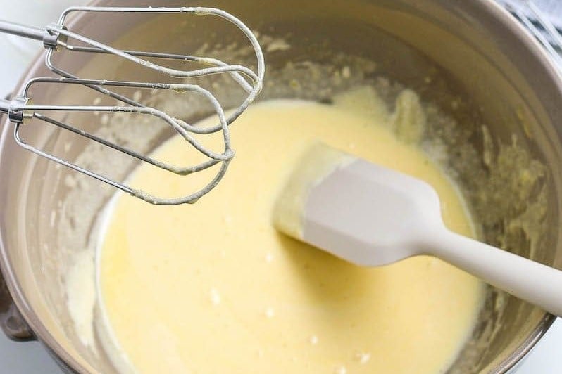 Homemade Eggnog mixture in a mixing bowl with a rubber scraper