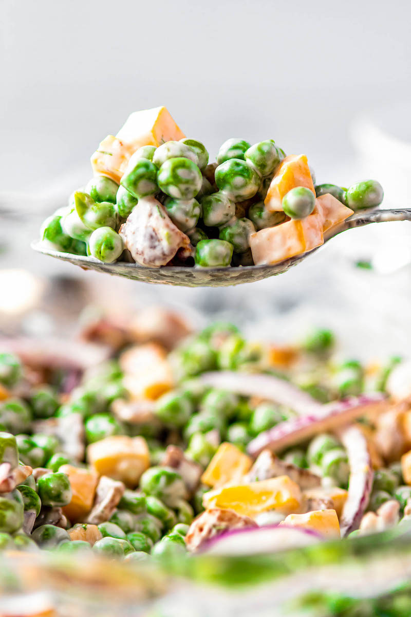 Spoonful of pea salad with cheese and bacon.