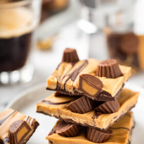 Pieces of chocolate peanut butter bark are stacked on a white plate.