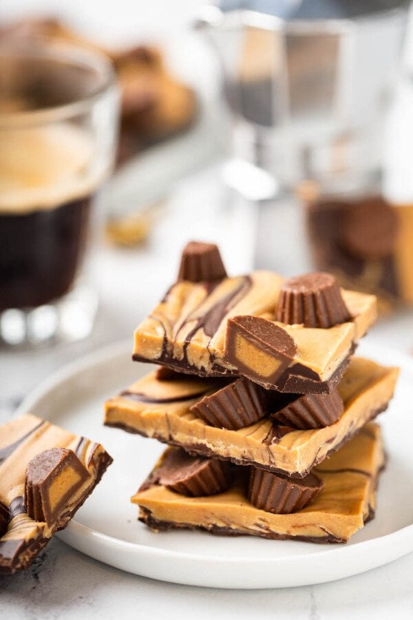 Pieces of chocolate peanut butter bark are stacked on a white plate.