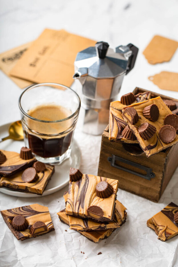 Pieces of bark are placed on a white surface, next to a glass of coffee.