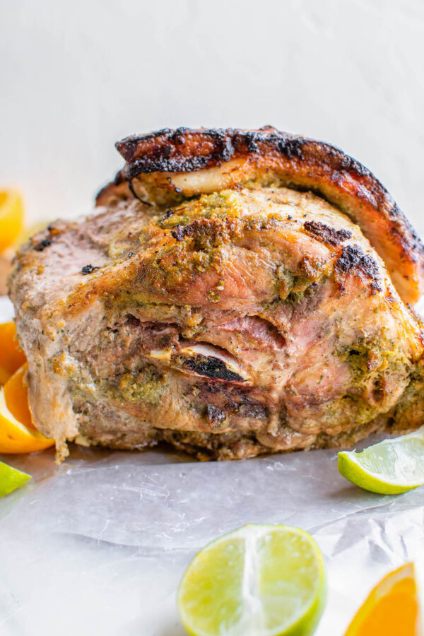 Side image of roasted pork with limes and orange slices. 