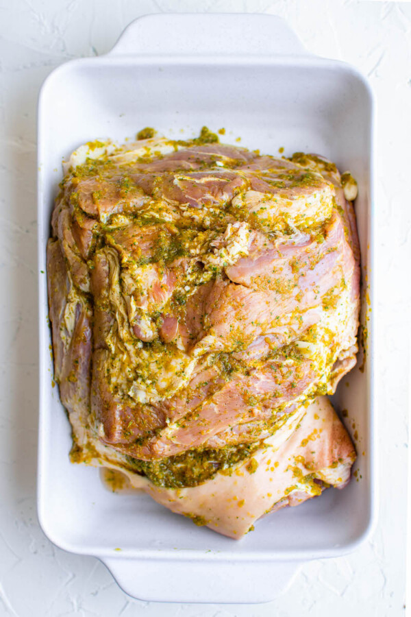 Uncooked pork is covered in green marinade.