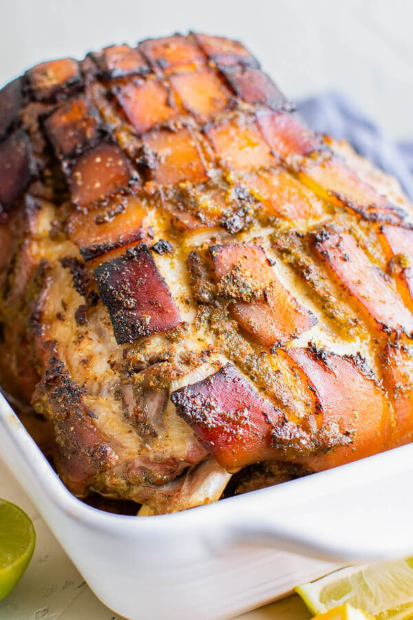 Freshly baked pernil is presented in a white baking dish.