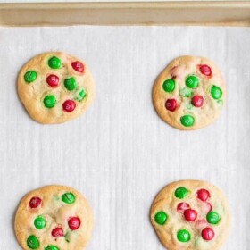Baked Red and Green M&M cookies on a parchment-lined baking sheet