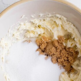 Top view of a mixing bowl with beaten butter, brown sugar and white sugar