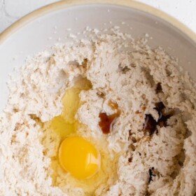 Top view of a mixing bowl with beaten butter and sugar with an egg and vanilla