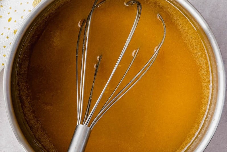 Amaretto sauce for Rumchata Pound Cake in a bowl with whisk
