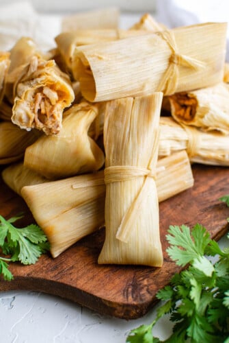 Tamales piled on a cutting board.
