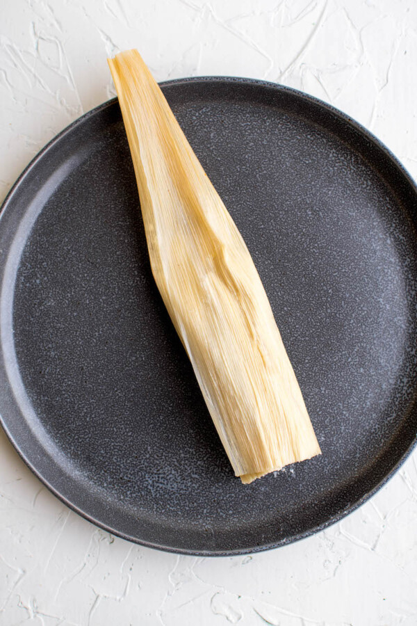Folded homemade tamale on a plate.