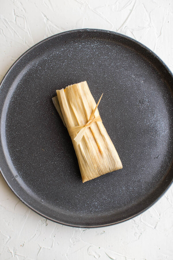 Tied homemade tamale on a plate.