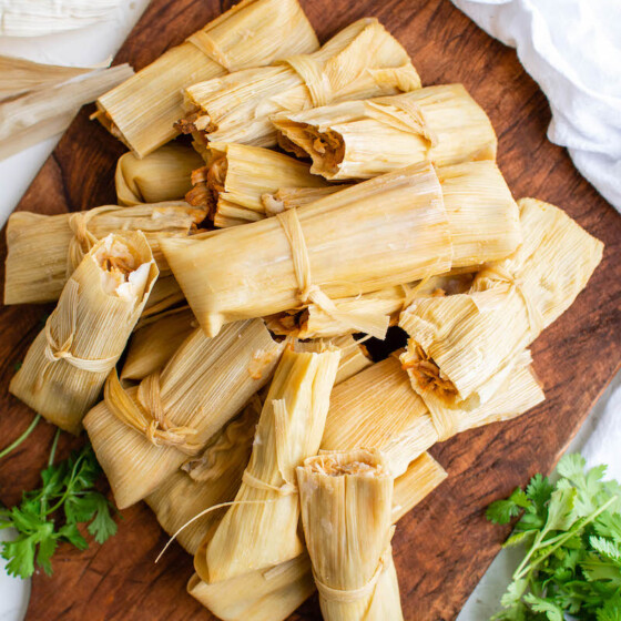 Pile of tamales on a wooden board.