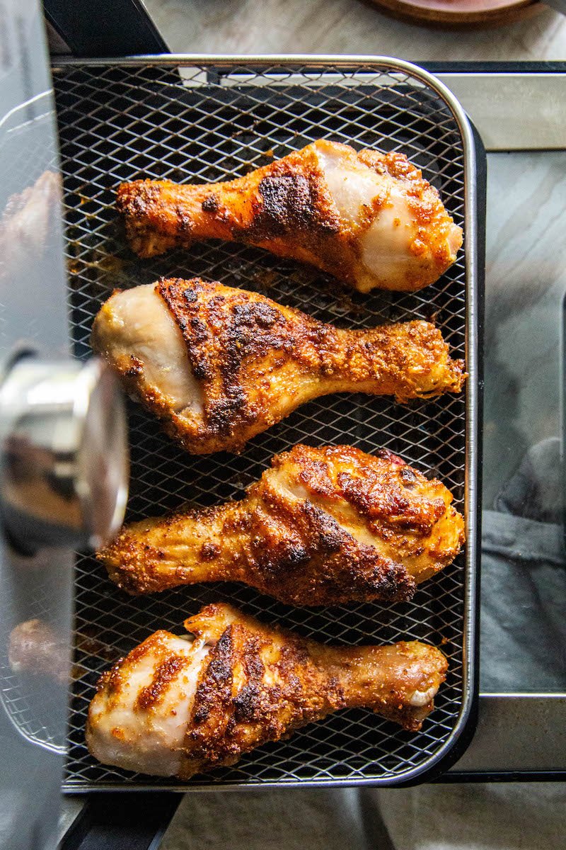 Chicken drumsticks on an air fryer tray.