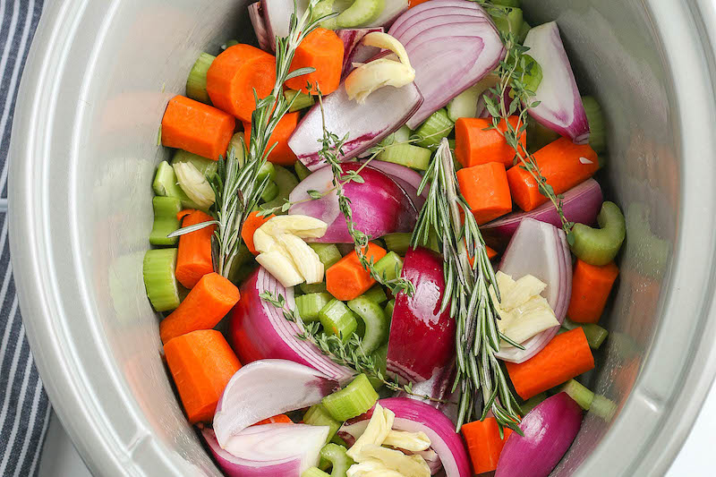 Overhead image of vegetables chopped and placed inside a crockpot.