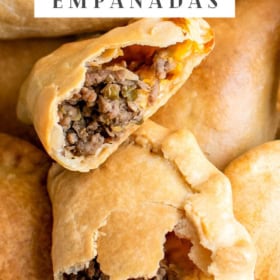 Up close image of a beef empanada torn in half sitting on top of other empanadas.