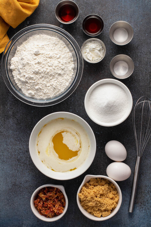 The ingredients for cookie dough are spread out on a dark surface.