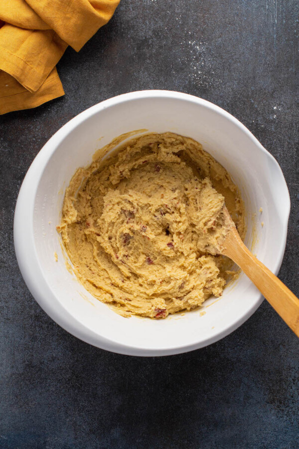 A wooden mixing spoon is stirring the dough.