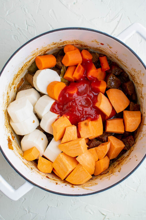 Peeled root vegetables in a soup pot.