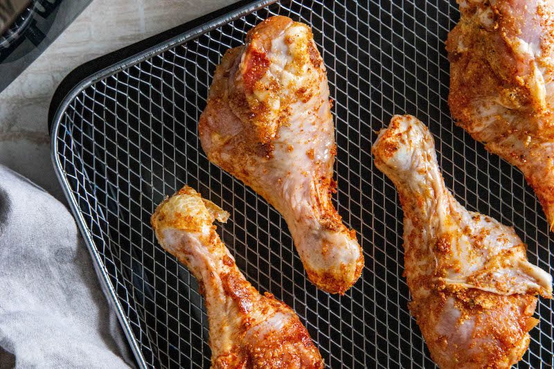 Chicken legs on an air fryer tray before going into air fryer.