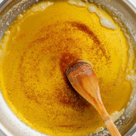 Brown butter in a silver skillet with a wooden spoon.