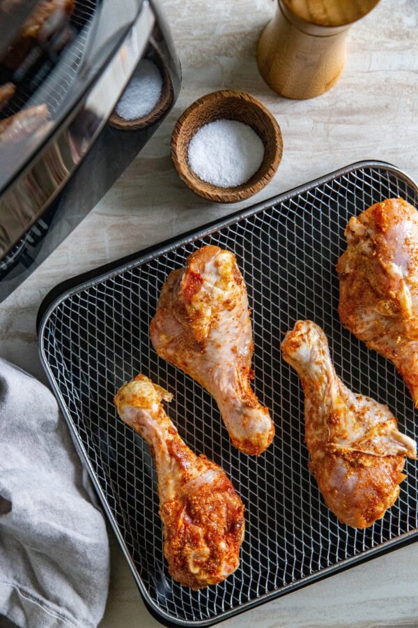 Seasoned chicken legs are placed on a wire rack. 