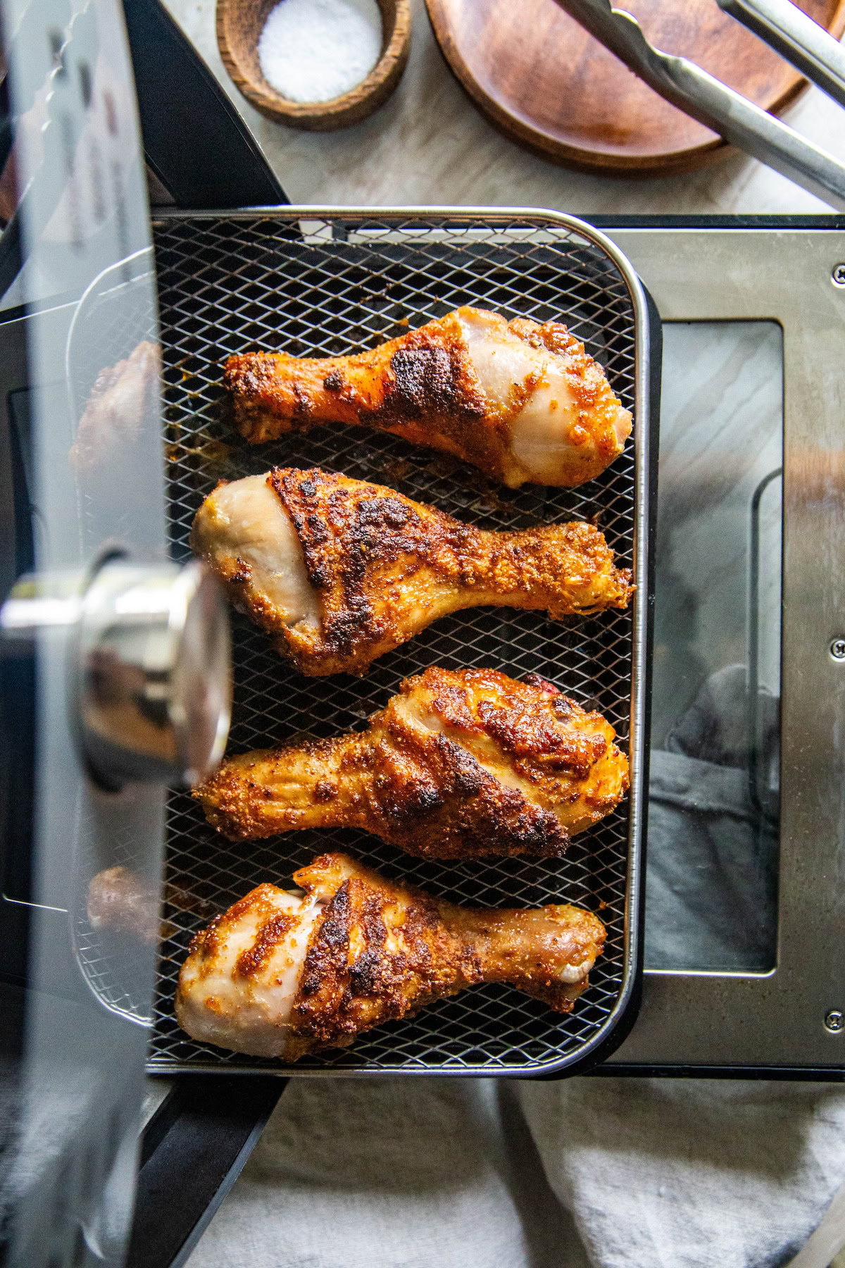 Crispy air fryer chicken legs are being removed from the air fryer. 