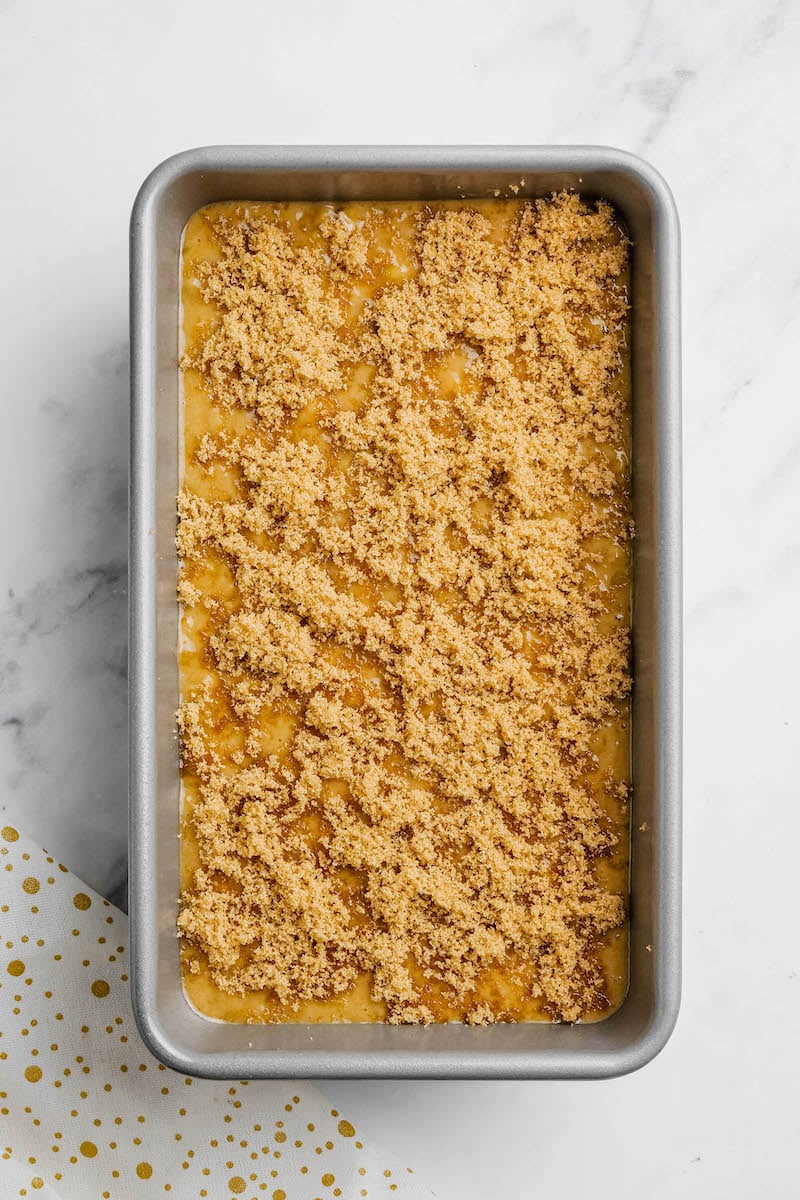 Banana bread batter in a pan, topped with brown sugar.