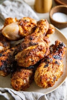 Air fryer chicken legs are stacked on a plate.