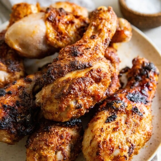 Air fryer chicken legs are stacked on a plate.