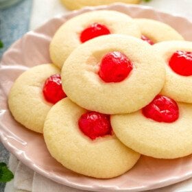 Cherry Almond Shortbread Cookies stack don a pink plate with a white napkin.