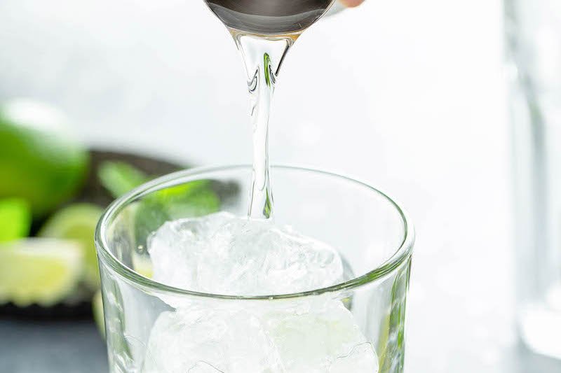 Up close image of rum being poured into a glass of ice.