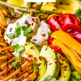 Image of chicken fajita salad in a bowl with avocado and sour cream on top.