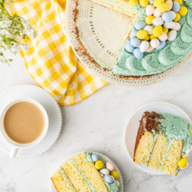 Overhead of easter cake on a cake plate with a yellow napkin and two slices of cake on plates.