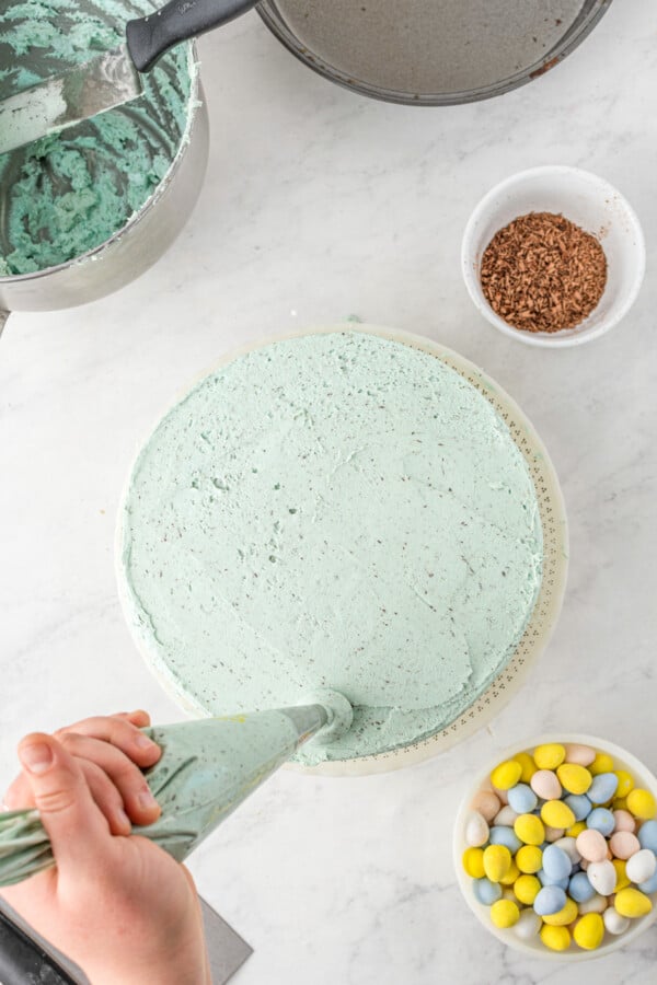 Frosting being piped onto the edge of a cake.