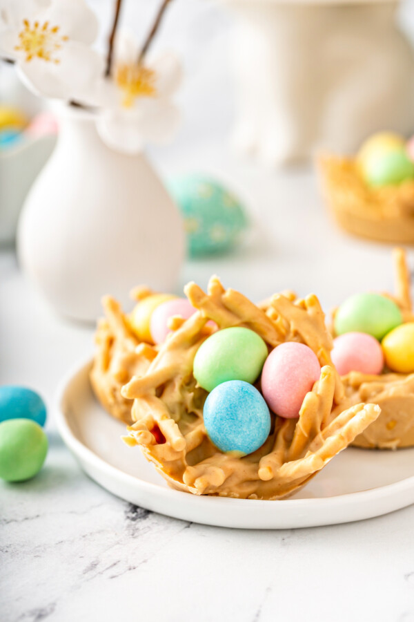 A haystack is topped with pink, green, and blue eggs.