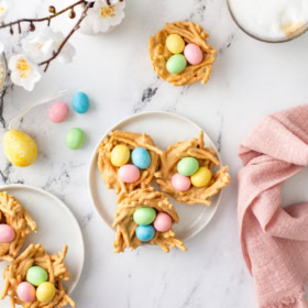 Overhead view of easter haystacks on a white marble background with white plate sand a pink napkin.