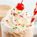 Chocolate milkshake with whipped cream and a cherry.