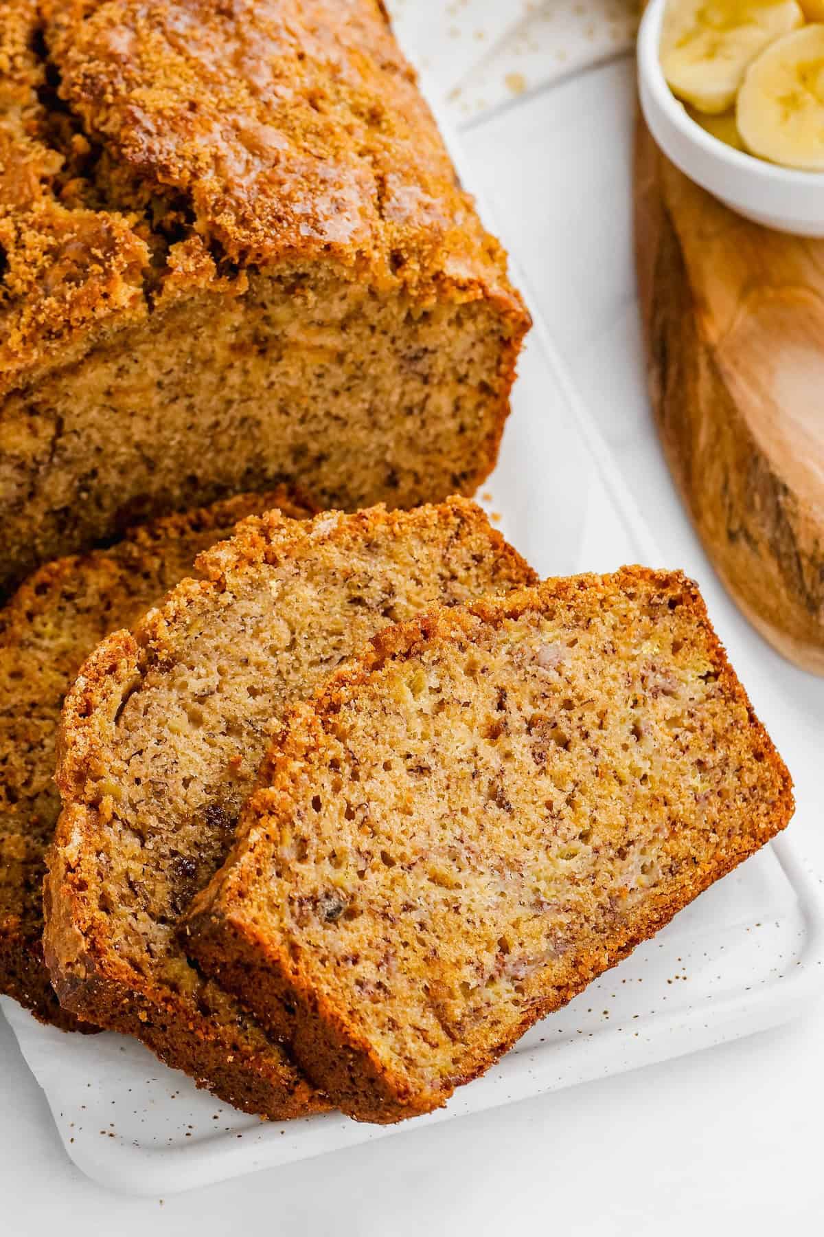 Slices of easy banana bread with brown sugar on a cutting board.