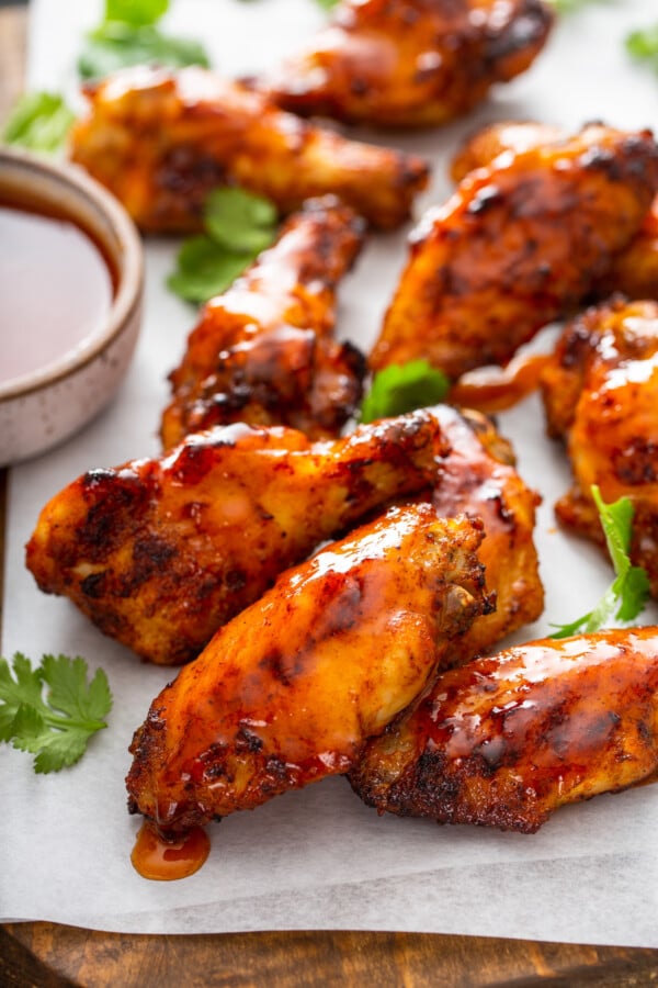 Up close image of hot honey wings covered in sauce on parchment paper. 