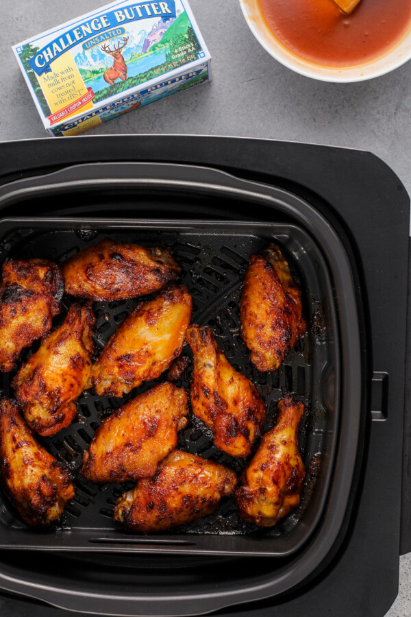 Overhead image of chicken wings being cooked in an air fryer. 