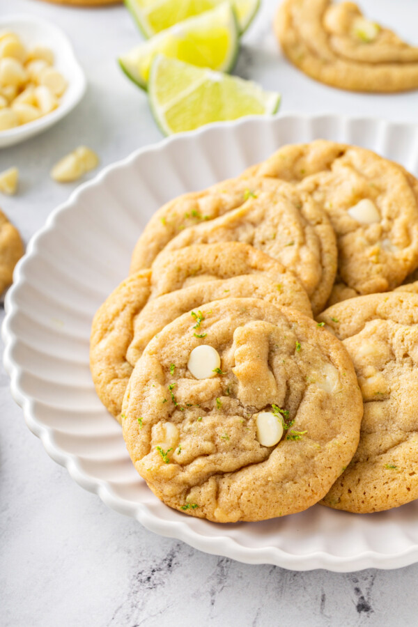 A plate of white chocolate chip cookies is placed on a marble counter.