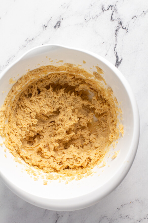 Dough has been mixed in a large white mixing bowl. 