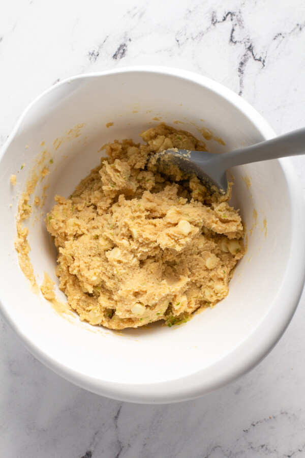 A large spoon has been placed in the bowl of cookie dough.