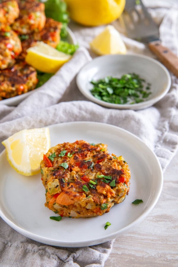 Salmon patty on a plate with lemon wedges.