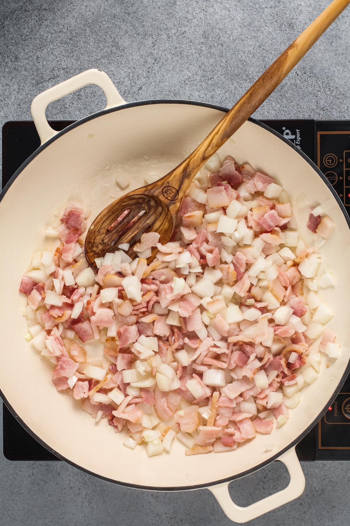 Thick cut bacon bits in a pan.