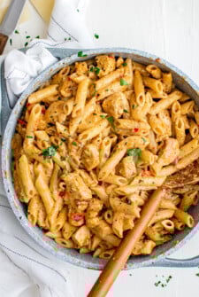 A pot of creamy pasta with chicken and peppers.